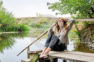 Young beautiful woman model with long blond hair sitting with different emotions laughter, sadness, sorrow, thoughtfulness on a wo Stock Photo