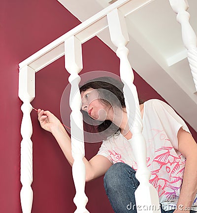 Young beautiful woman painting a ledge ballustrade white with a brush Stock Photo