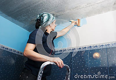 Young beautiful woman paints the wall Stock Photo