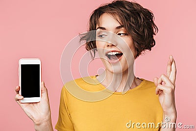 Young beautiful woman posing isolated over pink wall background using mobile phone showing display and hopeful please gesture Stock Photo