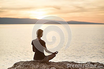 Young woman practicing yoga near the sea at sunset. Harmony, meditation and travel concept. Healthy lifestyle Stock Photo