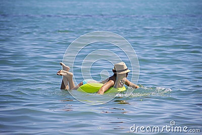 Young beautiful woman is relaxing in blue sea with rubber ring. Stock Photo