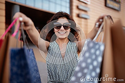 Young beautiful woman shopaholic walks out the shopping center with a pack of bags with purchases. Pink shopper in the hand of an Stock Photo