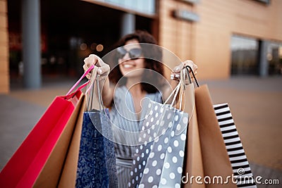 Young beautiful woman shopaholic walks out the shopping center with a pack of bags with purchases. Pink shopper in the hand of an Stock Photo