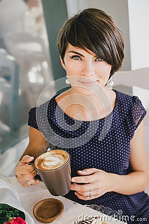 Young beautiful woman with short hair drinking steaming coffee Stock Photo