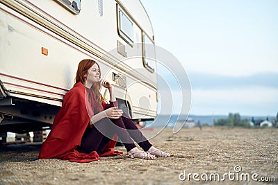 Young beautiful woman sits on a beach near a trailer, sea, vacation Stock Photo