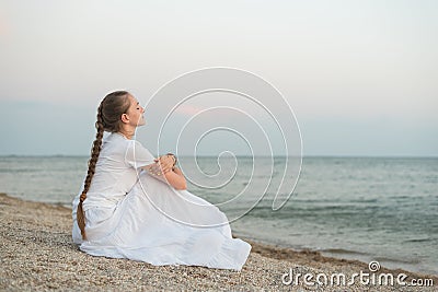 Young beautiful woman sitting on sandy beach against sea and dreams. keep calm Stock Photo