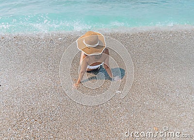 Young beautiful woman is sitting on the sea cost and enjoying waves landscape. Alanya, Turkey Stock Photo