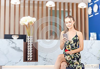 Young beautiful woman sitting on suitcases at the front desk hotel reception, Female with bag travel luggage at the reception Stock Photo