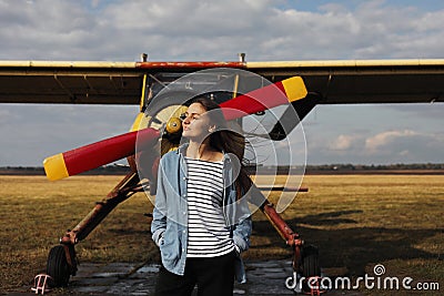 Young beautiful woman standing near the plane. Traveling and technology Stock Photo