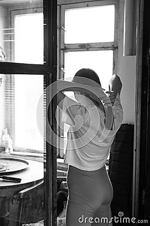 young beautiful woman stands near the window, black and white photo Stock Photo