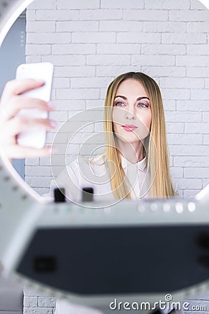 Young and beautiful woman taking selfie with mobile phone in light of the ring lamp Stock Photo