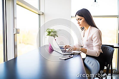 Young beautiful woman using her laptop while sitting in chair at her working place Stock Photo