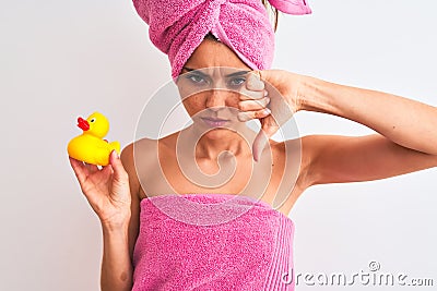 Young beautiful woman wearing shower towel holding duck over isolated white background with angry face, negative sign showing Stock Photo