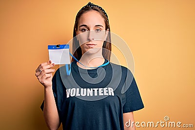 Young beautiful woman wearing volunteer t-shirt doing volunteering holding id pass card with a confident expression on smart face Stock Photo