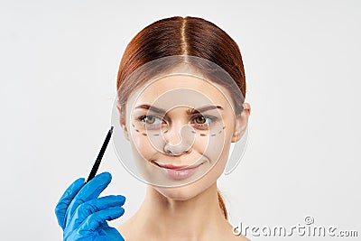 Young beautiful woman on white background holds a marker, plastic surgery, facial contour, portrait Stock Photo