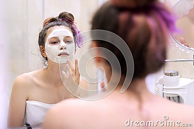 Young beautiful woman with white cosmetic natural healing mask on face Stock Photo