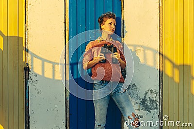 Young Beautiful Women Stands Near Colorful Wall With Binoculars Stock Photo
