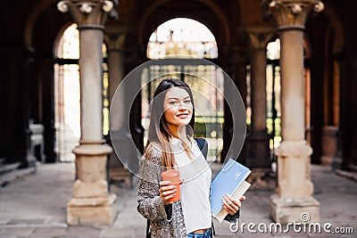 Young beauty student girl with notebooks outdoors the university drink a cup of coffee Stock Photo