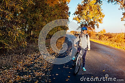 Young bicyclist riding in autumn field at sunset. Happy woman smiling Stock Photo