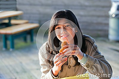 Young biracial teen girl eating hamburger Stock Photo