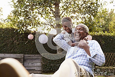 Young black boy embracing grandfather sitting in garden Stock Photo