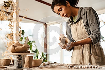 Young black ceramist woman sculpting in clay at her workshop Stock Photo