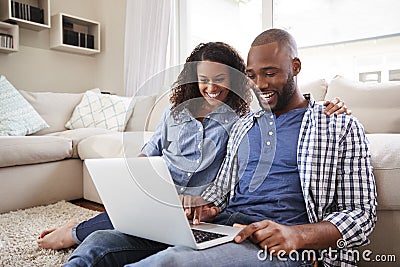 Young black couple using laptop sitting on the floor at home Stock Photo