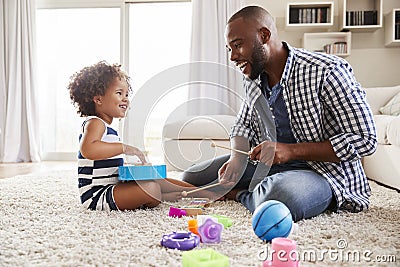 Young black father playing with daughter in the sitting room Stock Photo