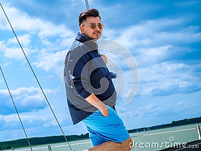 Young black hair man wear in sunglasses and nautical cloth standing on a sailing boat during his summer sailing voyage Stock Photo