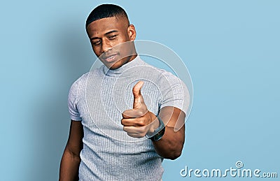 Young black man wearing casual t shirt looking proud, smiling doing thumbs up gesture to the side Stock Photo