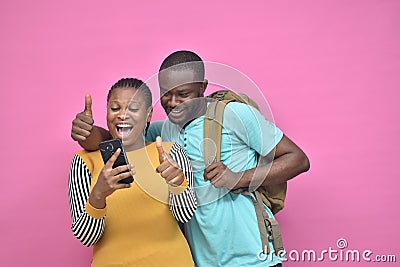 young black man and woman feeling excited and happy viewing content on a mobile phone together Stock Photo