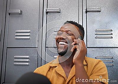 A young black student laughs on a phone call in front of campus lockers Stock Photo