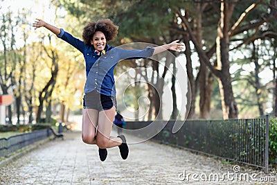 Young black woman with afro hairstyle jumping in urban background Stock Photo