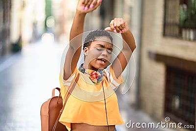 Young black woman is dancing on the street in Summer. Girl traveling alone. Stock Photo