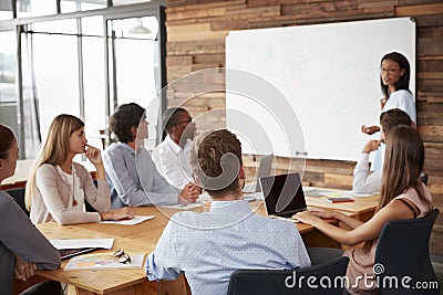 Young black woman presenting to colleagues from whiteboardï¿½ Stock Photo