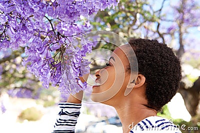 Young black woman smelling flowers on tree Stock Photo