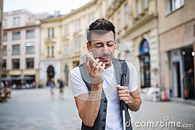 Young blind man with smartphone on street in city, making phone call. Stock Photo