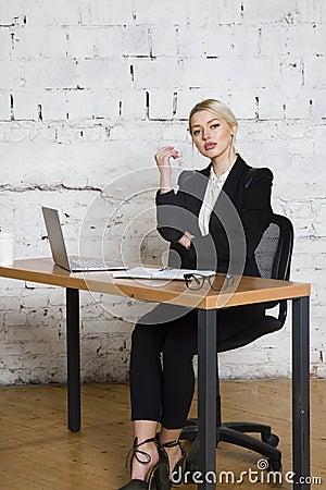 Young blond beauty businesswoman sitting at a office table with laptop, notebook and glasses in suit. Business concept. Stock Photo