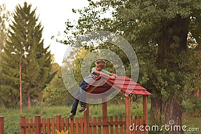 Young blond boy leaning on the red roof top playground house Editorial Stock Photo