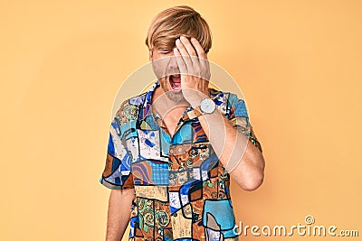 Young blond man wearing summer shirt yawning tired covering half face, eye and mouth with hand Stock Photo