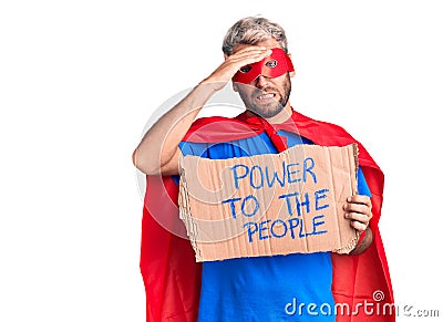 Young blond man wearing super hero custome holding power to the people cardboard banner stressed and frustrated with hand on head, Stock Photo