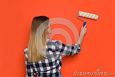 Young Woman Painting Orange Wall. Rear View Stock Photo