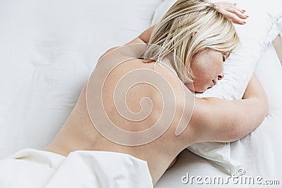 Young blond woman sleeping on her stomach in bed. Full sleep and relaxation Stock Photo