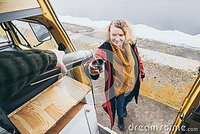 Young blond woman standing next to camper van overlooking the sea Stock Photo