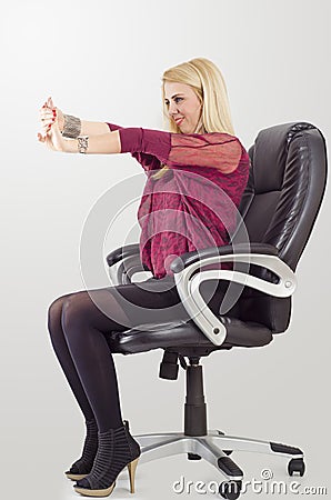 Young blonde businesswoman doing stretching, while sitting in chair Stock Photo