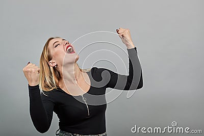 Young blonde girl in black jacket happy woman reacts with smile raises hands up Stock Photo