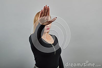 Young blonde girl in black jacket woman stops with hand gesture Stock Photo