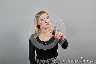 Young blonde girl in black jacket woman warns by pinching her index finger Stock Photo