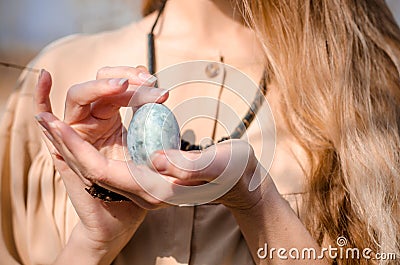Young blonde girl in boho style dress, near tree with blue egg like dragon egg, photo for cover of book, movie or album Stock Photo